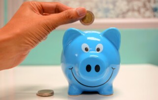 person putting coin in a piggy bank